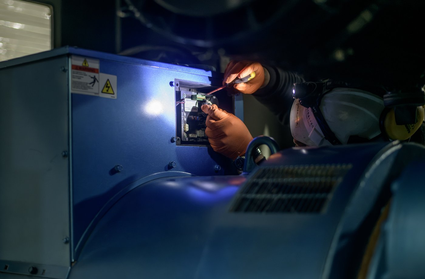 Técnico Australtec revisando el motor de un grupo electrógeno con linterna frontal